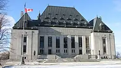 Large grey building in winter, with a Canadian flag in front