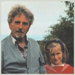 A vintage-styled photograph of a man and a girl looking at the camera.