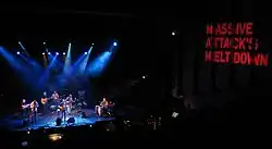 Callier and his band onstage as shot from above with a large Massive Attack banner on the side