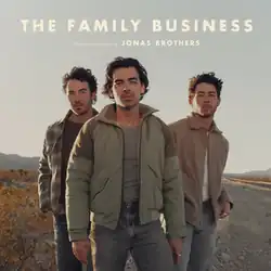 The three brothers standing in the desert in a triangular position facing forward.