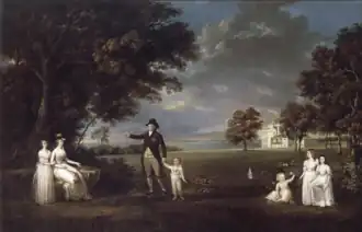Family standing and sitting in front of an English estate landscape.