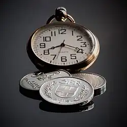 A photograph of a watch and three coins.