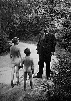 Two nude boys walking down road to a swimming hole