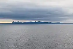 Ugamak Island as seen from the Bering Sea looking east towards Unimak Island. Ugamak is in the foreground and Shishaldin and Isanotski volcanoes on Unimak Island are in the background.