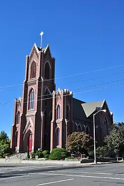 A modern photo of a brick church building with a prominent tower