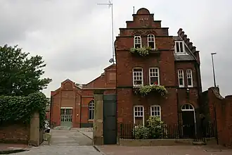 A multi-story brick building with many windows, varied rooflines, and a large arched entryway.