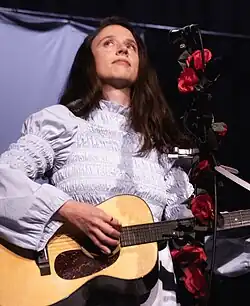 Photo of Katie Crutchfield playing acoustic guitar on festival stage