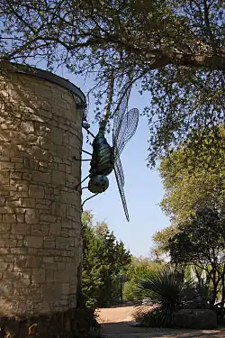 Giant dragonfly sculpture on a limestone water tower.