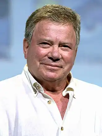 A man with short, brown hair, looking slightly upwards to the camera while smiling.