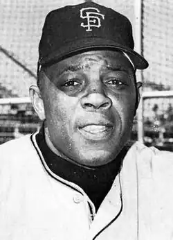 Photographic portrait of an older Willie Mays in a San Francisco Giants uniform, the top button of which is undone