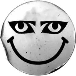 The World Goth Day logo, resembling a silver sticker with a black smiley face with eyeliner