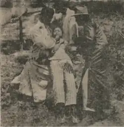 A grainy image of a man killing a woman as two men support her body